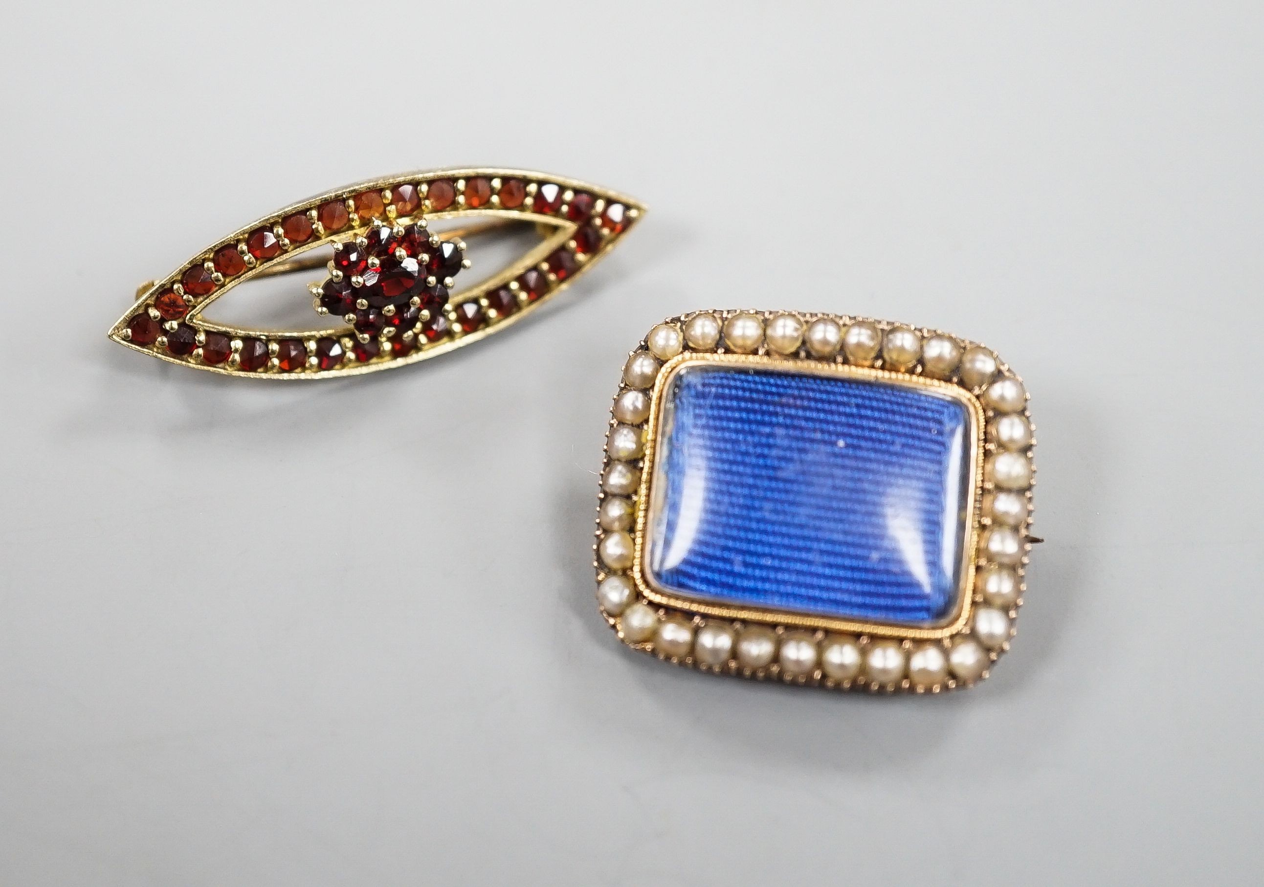 A Victorian yellow metal and spit pearl set mourning brooch, 23mm and 900 git white metal and garnet set brooch.